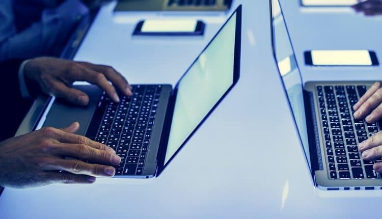 Hand on a laptop working at cyber space table