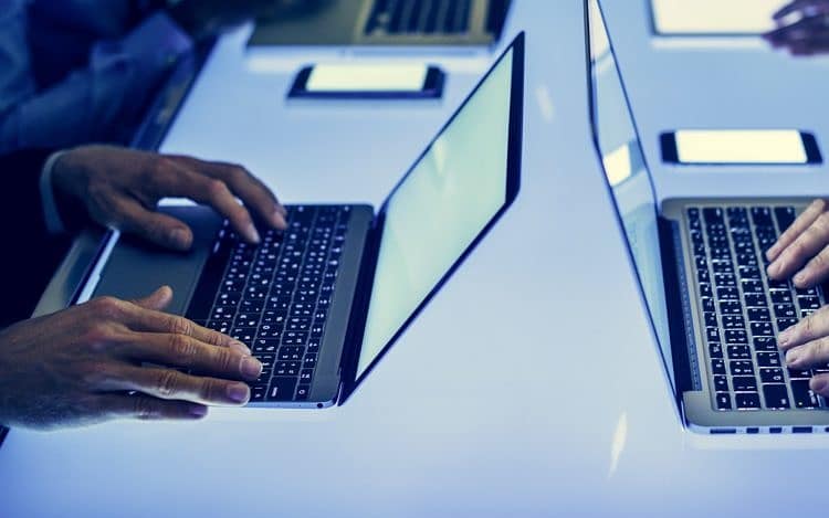 Hand on a laptop working at cyber space table