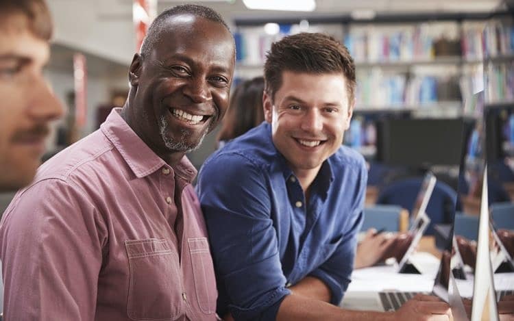 Mature Male Student With Tutor Learning Computer Skills