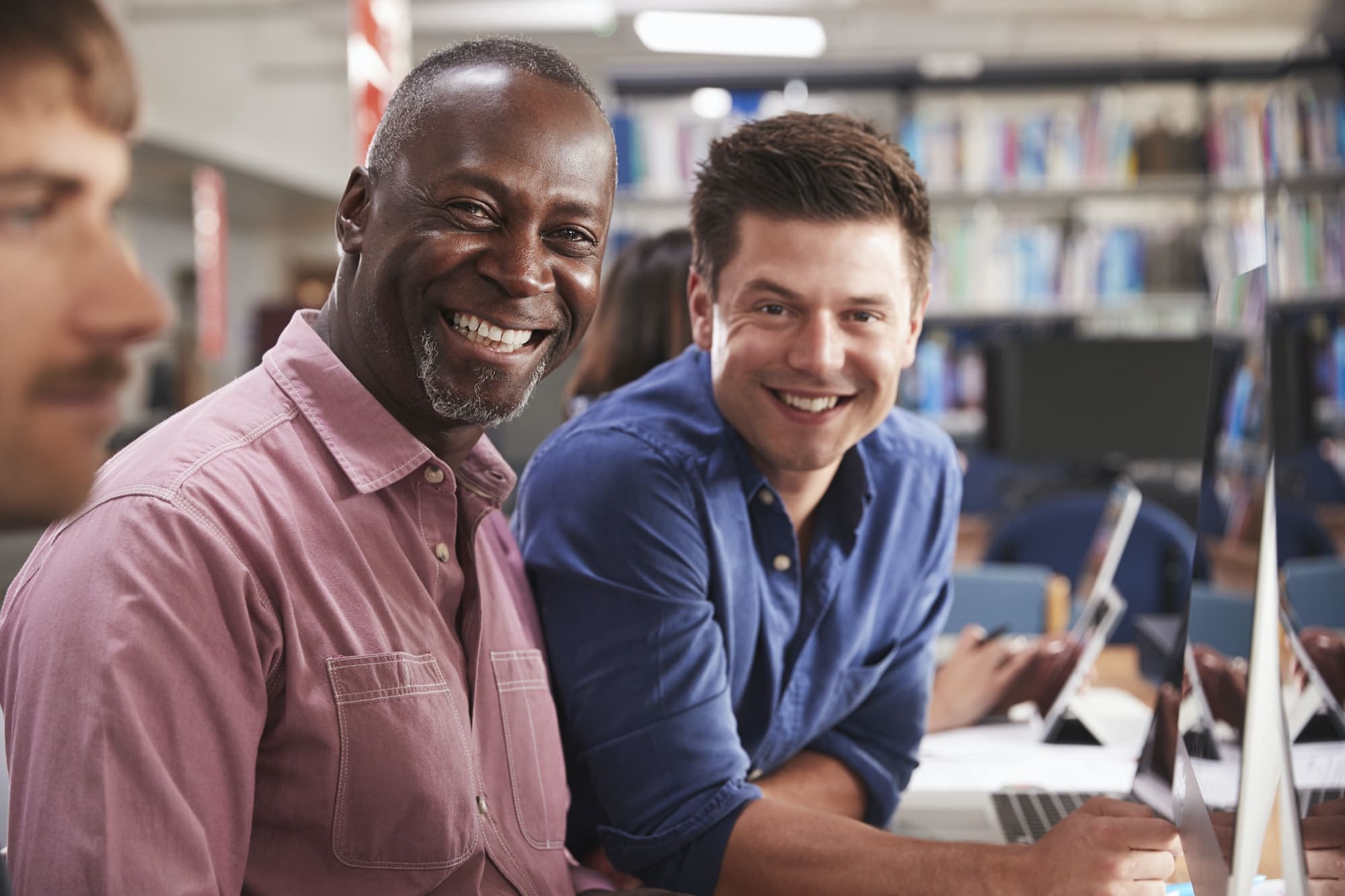 Mature Male Student With Tutor Learning Computer Skills