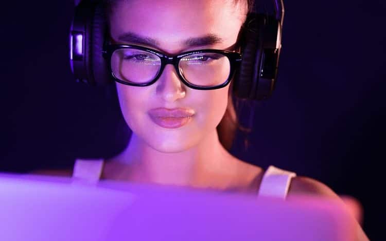 Student watching online tutorials, wearing headphones in the night