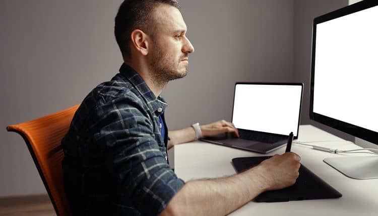 Young man working with interactive pen display and computer