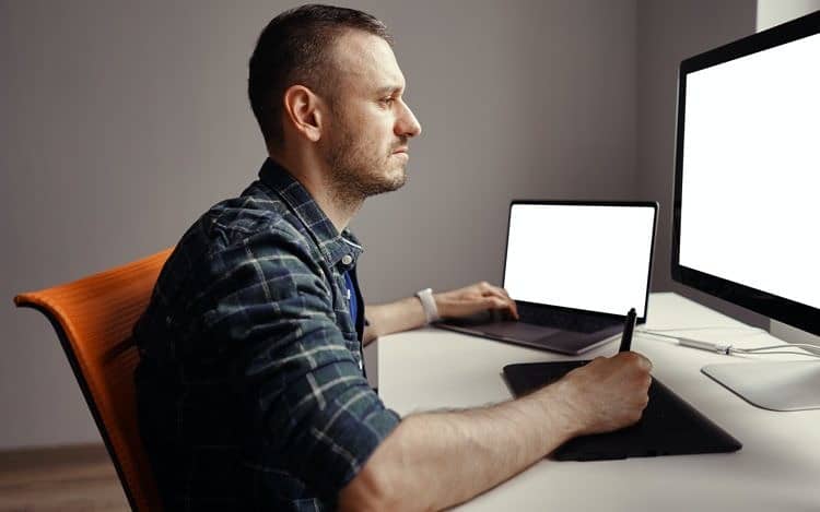 Young man working with interactive pen display and computer