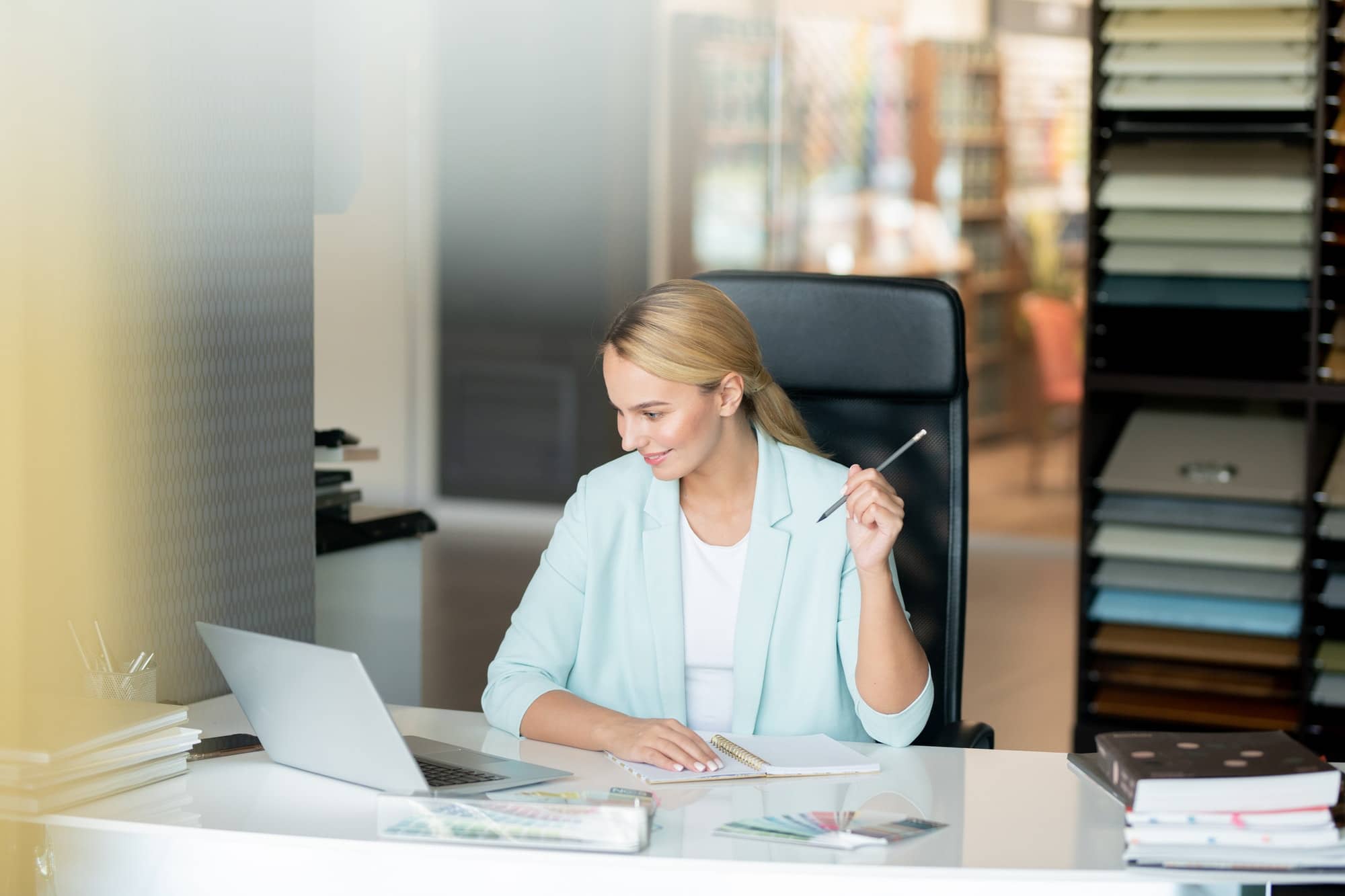 Clever young female student sitting by desk while watching online video