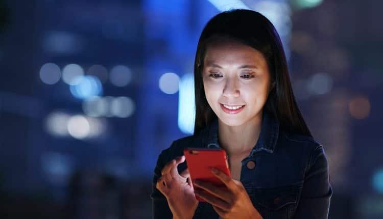 Woman work on smart phone over business district at night