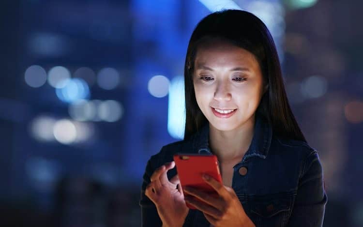 Woman work on smart phone over business district at night