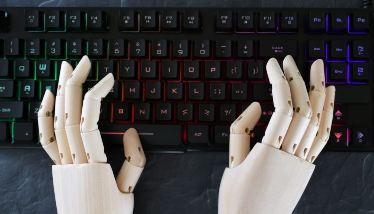 AI artificial intelligence concept - robot hands typing on lit keyboard