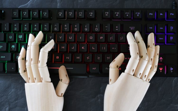 AI artificial intelligence concept - robot hands typing on lit keyboard