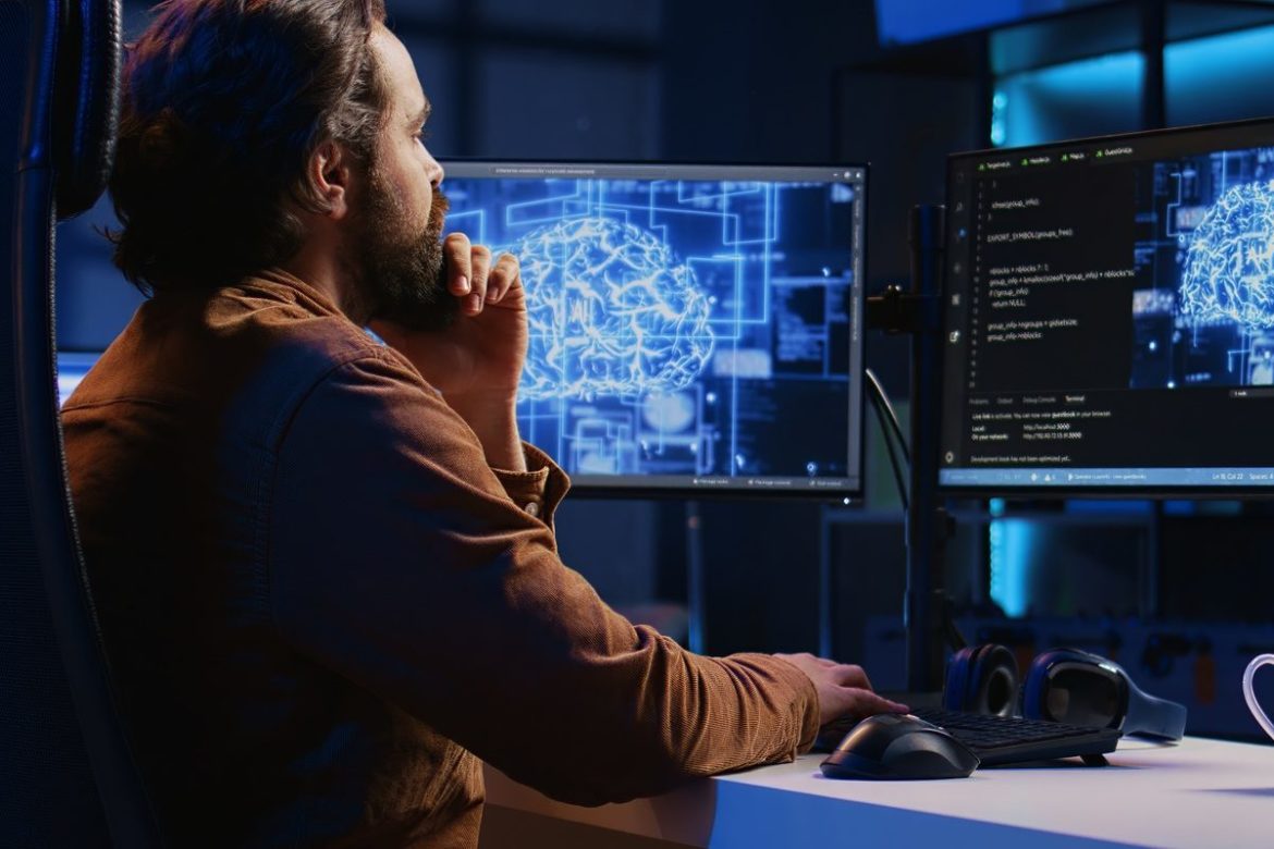 Freelancing programmer writes artificial intelligence code on desktop PC