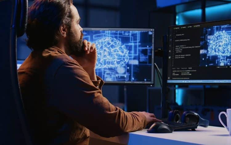 Freelancing programmer writes artificial intelligence code on desktop PC