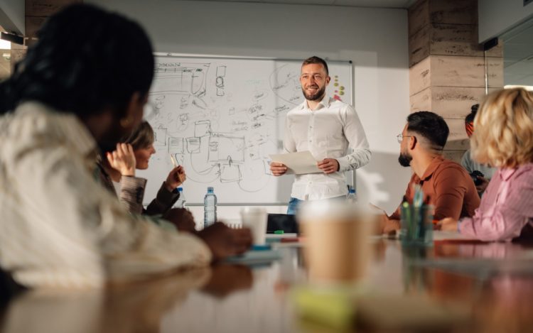 Marketing team listening to project manager giving presentation in meeting room