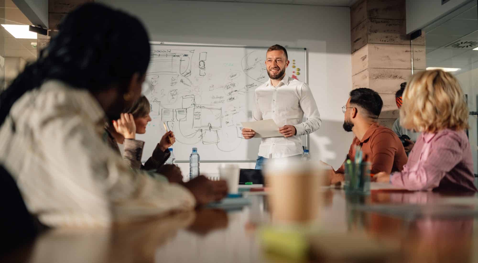 Marketing team listening to project manager giving presentation in meeting room