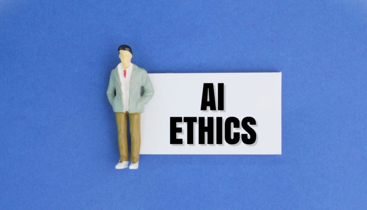 miniature people and paper with the word AI ETHICS. Ethical concepts for artificial intelligence
