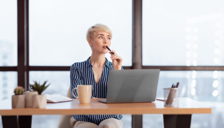 Pensive Businesswoman At Laptop Thinking On A Task In Office