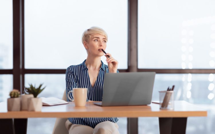 Pensive Businesswoman At Laptop Thinking On A Task In Office