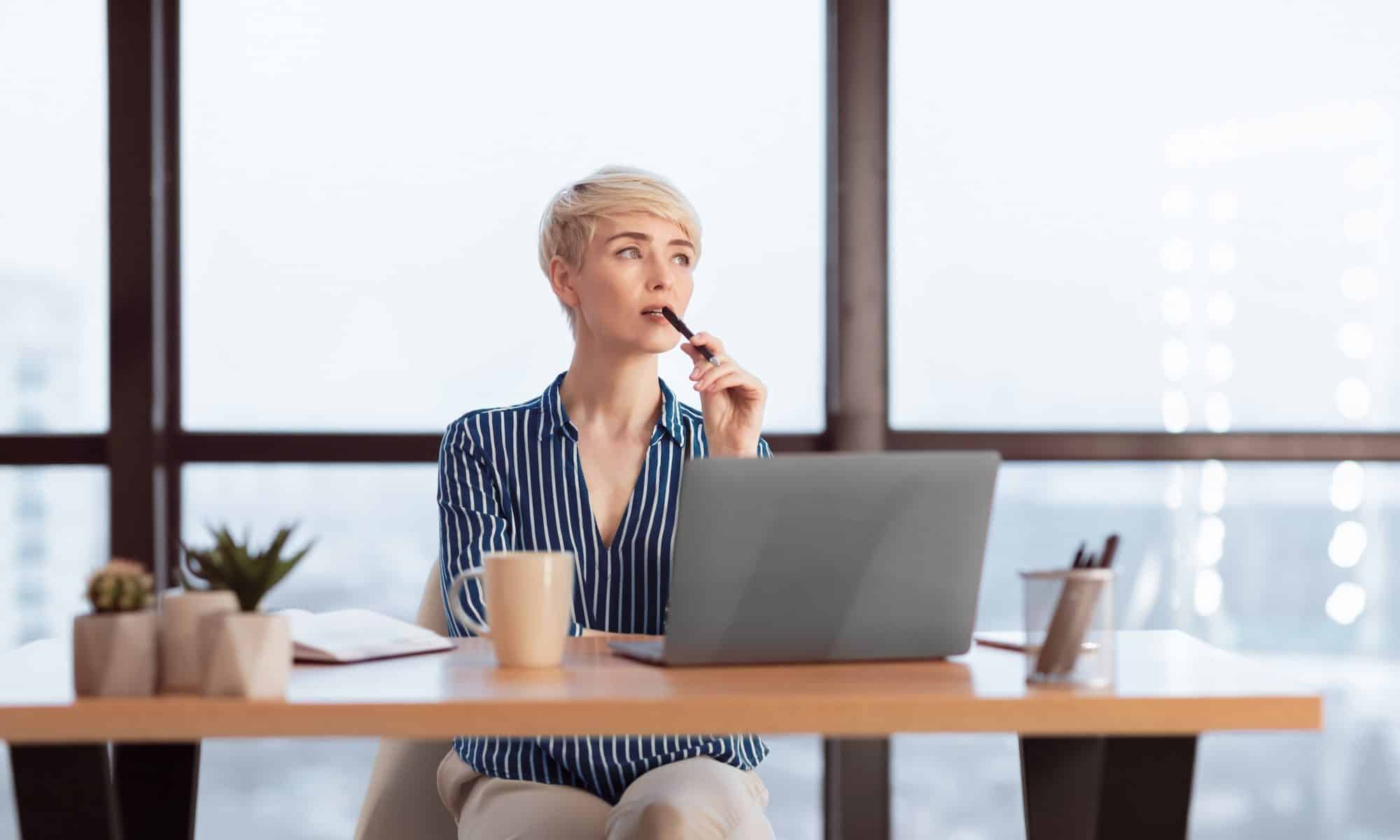 Pensive Businesswoman At Laptop Thinking On A Task In Office