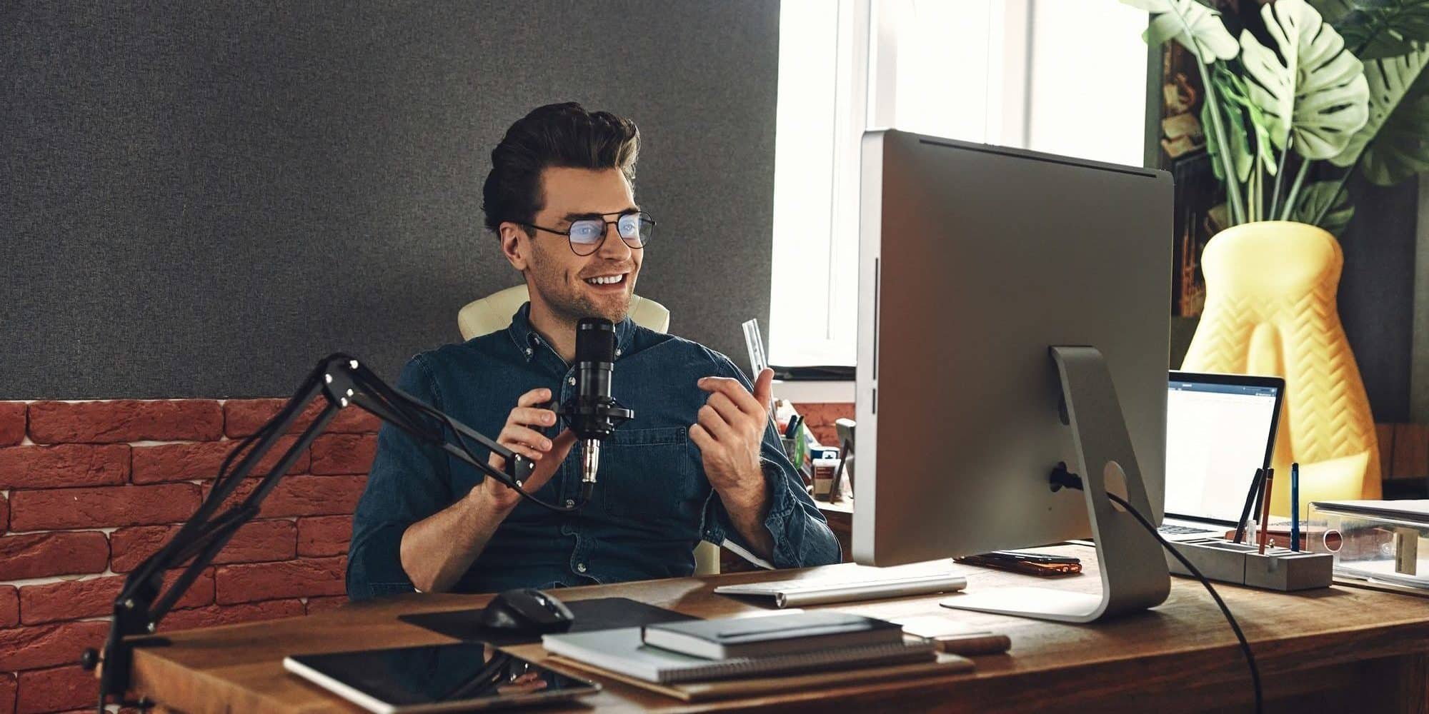 Handsome young man using microphone and gesturing while recording podcast in studio