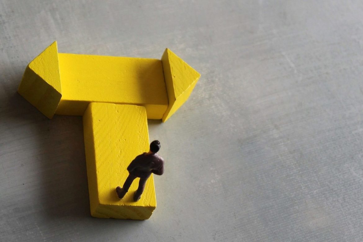 Miniature man standing at a turning point. Copy space for text.