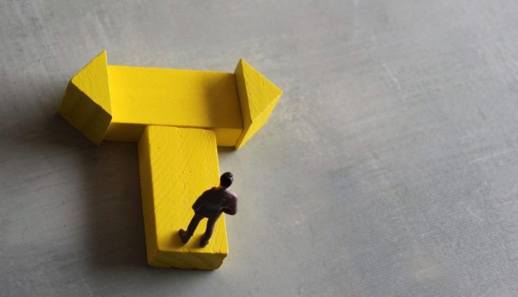 Miniature man standing at a turning point. Copy space for text.