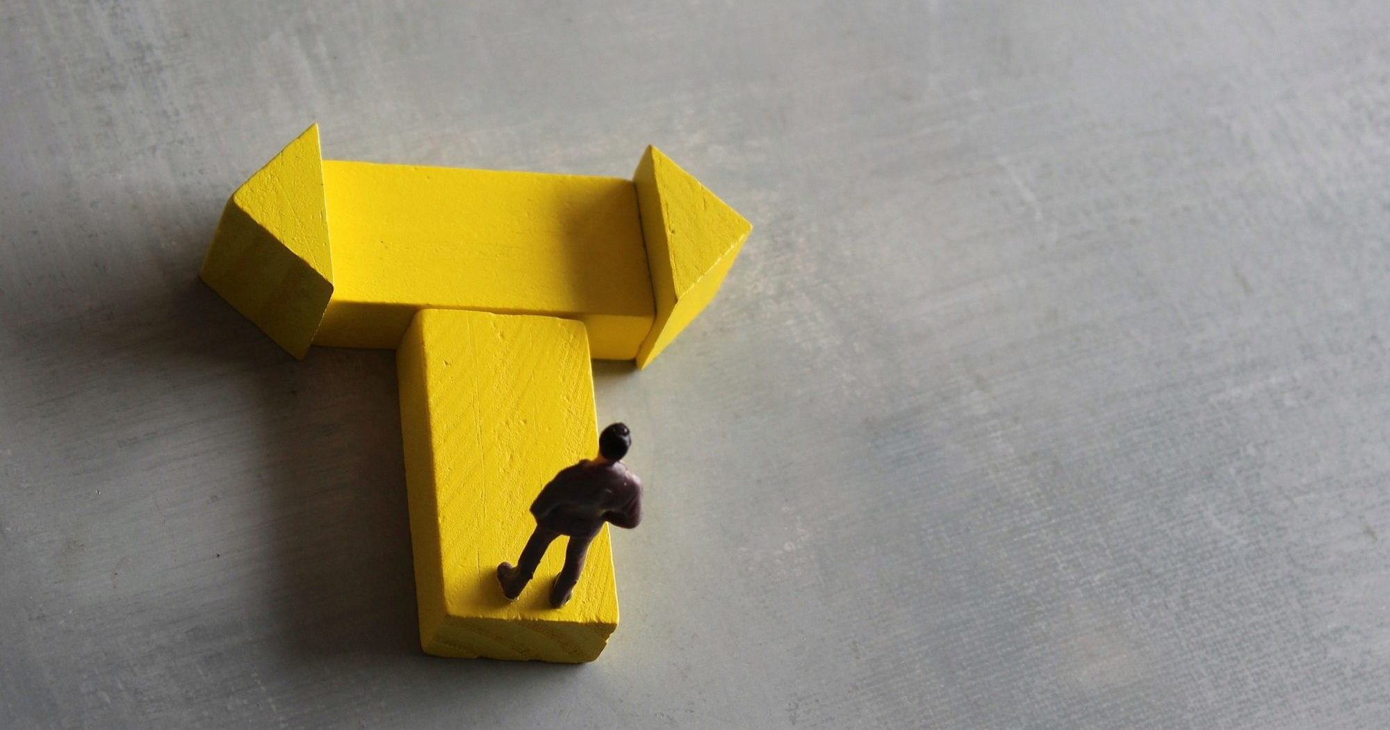 Miniature man standing at a turning point. Copy space for text.