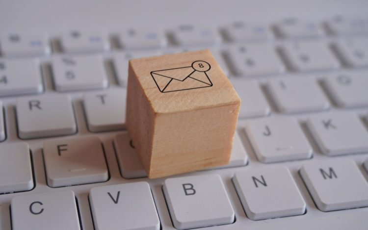 Wooden cube with new email notification icon on top of keyboard.