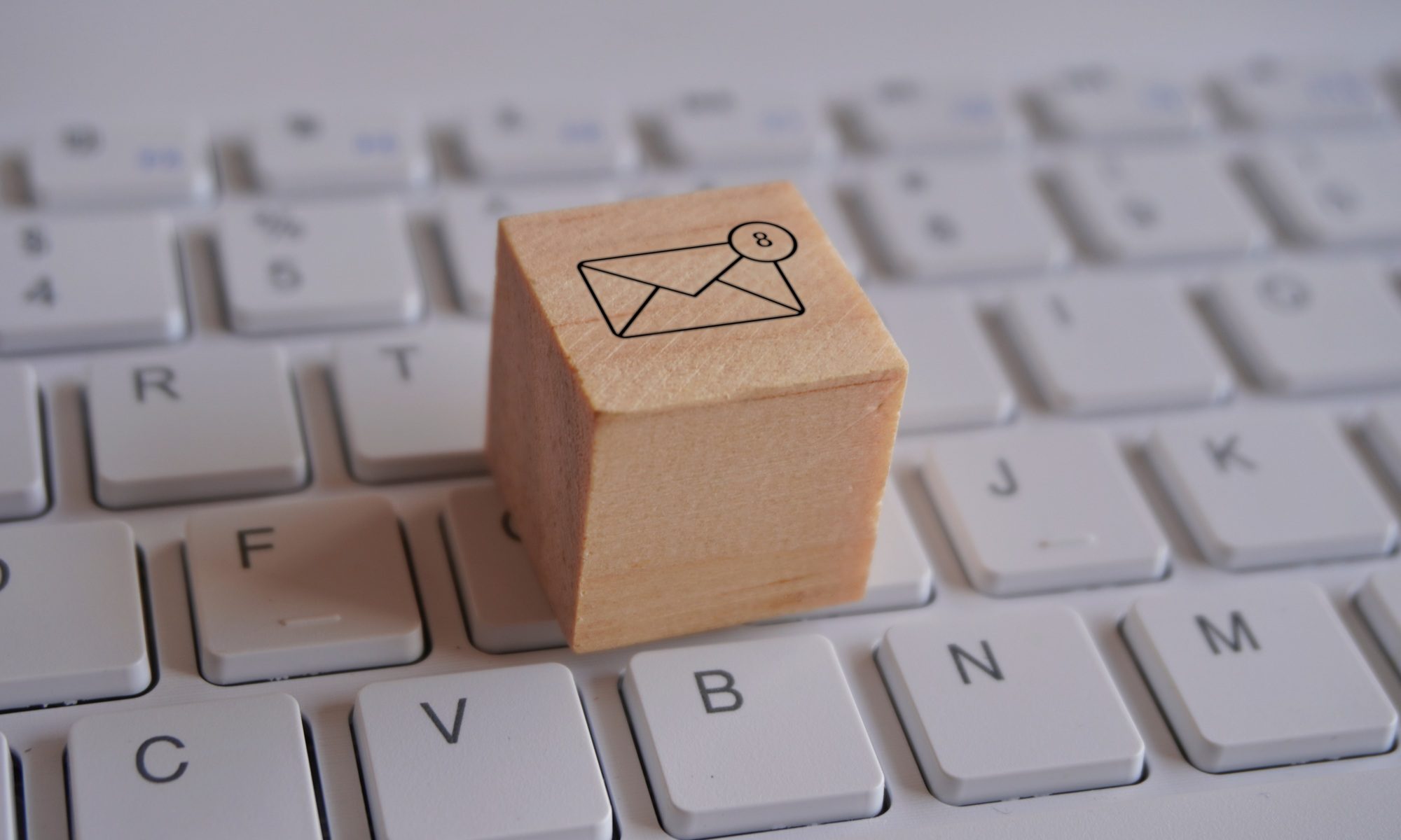 Wooden cube with new email notification icon on top of keyboard.